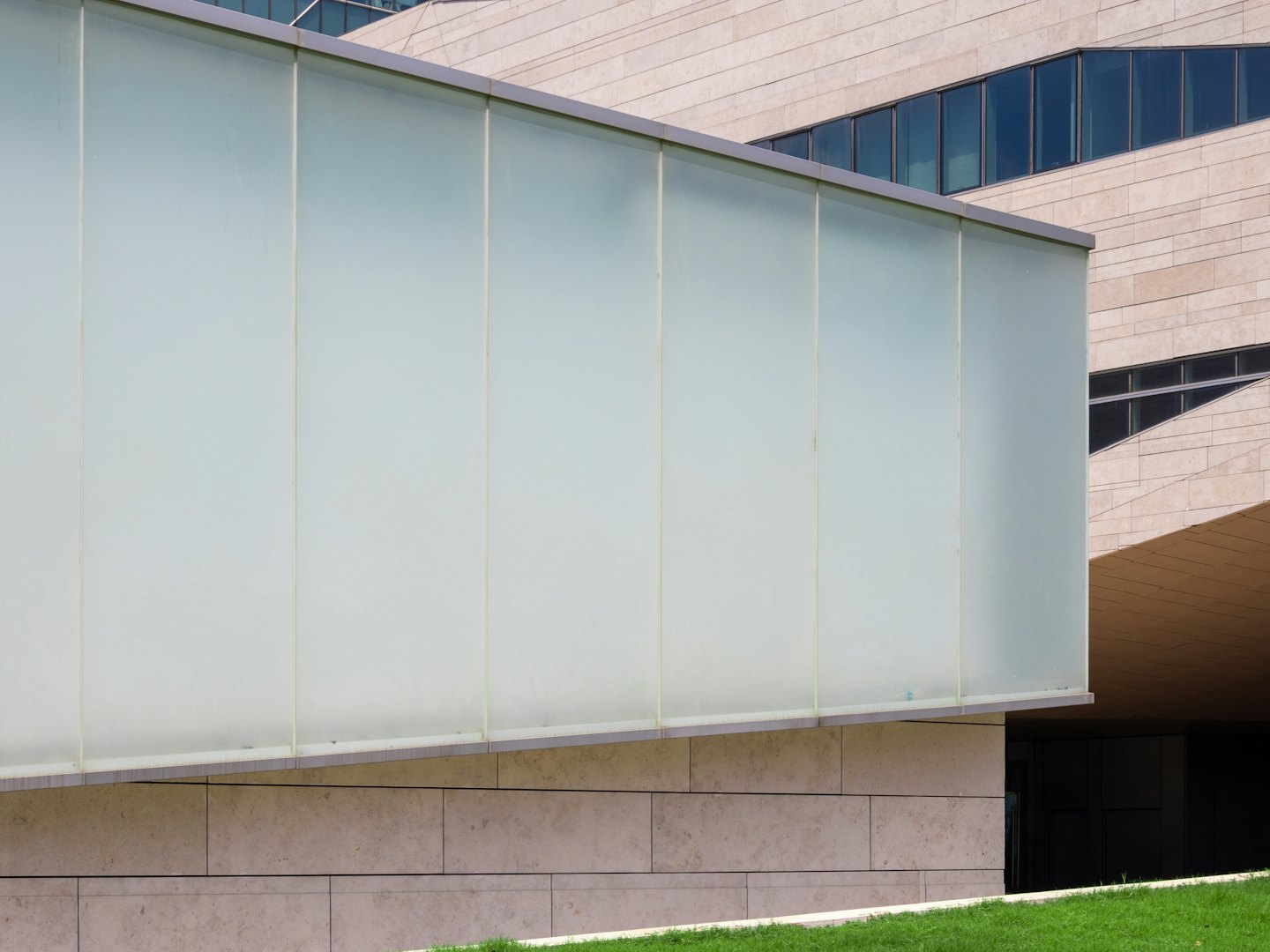 Frosted glass paneling extends from a beige stone building.